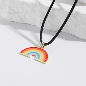 Detail of colorful rainbow heart pendant with gold metal edges on a black braided rope necklace