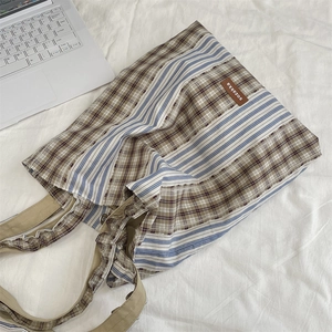 Detail of vintage patchwork tote bag showing blue stripes and brown plaid canvas textures