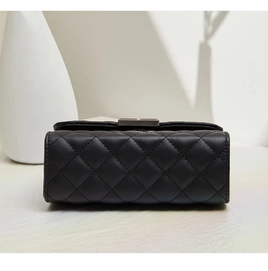 Detail of black quilted leather texture and silver metal lock on women's chain bag