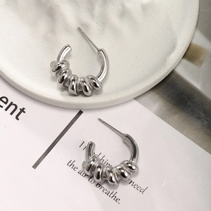 Detailed close-up of silver-tone twisted C-shape hoop earrings with textured spiral finish