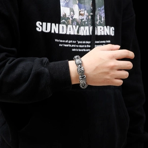 Close-up of men's vintage steel bracelet with intricate totem carvings on wrist