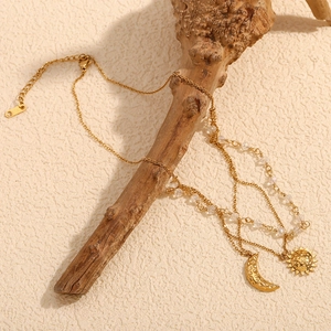 Multi-layer 18K gold plated necklace with sun and moon pendants on a rustic wood branch