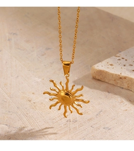 Détail du collier avec pendentif soleil plaqué or 18K sur une surface en pierre texturée