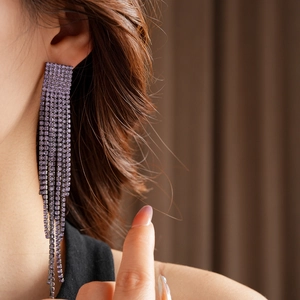 Gros plan d'un mannequin portant des boucles d'oreilles à pompons en strass violets