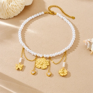 Vintage pearl necklace with gold-plated flower and butterfly pendants on sand background