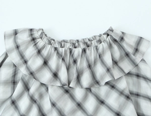Close-up of gray and white plaid blouse featuring delicate ruffled neckline details