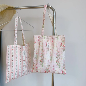 Detail of pink floral and striped cotton tote bags with shoulder straps and woven labels