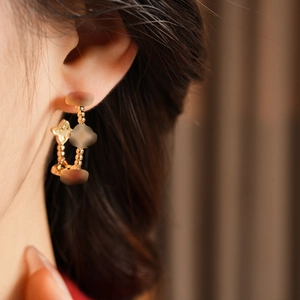 Detailed macro view of 18k gold plated flower drop hoop earrings worn by a model