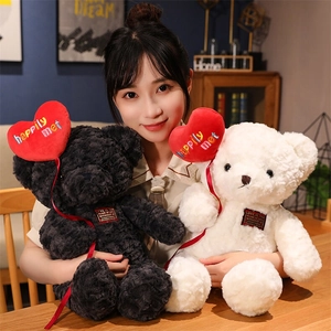 Close-up of black and white teddy bears holding red heart balloons in a cozy setting
