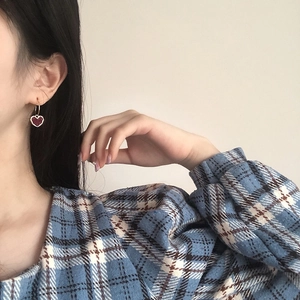 Elegant gold heart earrings with deep red resin charms worn by a model in a casual setting