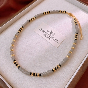 Detail of beaded agate necklace with gold lobster clasp and extension chain on velvet