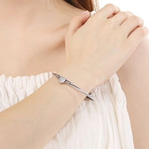 Bracelet en câble d'acier argenté avec pendentif cœur porté au poignet d'un modèle