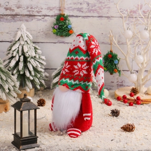 Standing Christmas gnome with red and green knit hat on artificial snow background