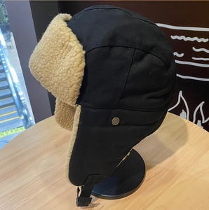 Dettaglio del cappello da aviatore nero con calda fodera in pile beige e bottoni in metallo