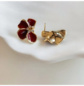 Détail de boucles d'oreilles fleurs en émail rouge plaquées or avec zircon