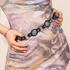 Detail of vintage punk belt featuring silver metal rings and turquoise stone inlays