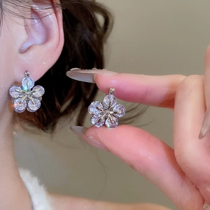 Close-up of sparkling zircon flower earrings featuring silver metal and a five-petal design