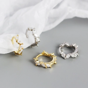 Macro detail of gold and silver hoop earrings with marquise-cut zircon stones