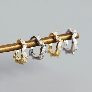 Macro shot of s925 silver hoop earrings with marquise-cut zircon inlay on a gold stand