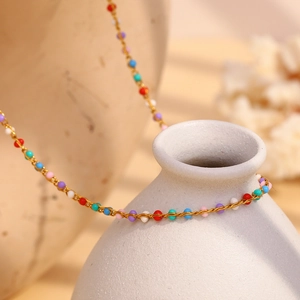 Colorful beaded necklace with 18K gold plated stainless steel chain on a ceramic vase
