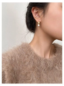 Macro shot of two-tone waterdrop earrings with S925 silver needle and pearl on model