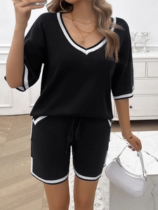 Detail view of women's black knit set with white V-neck trim and drawstring shorts