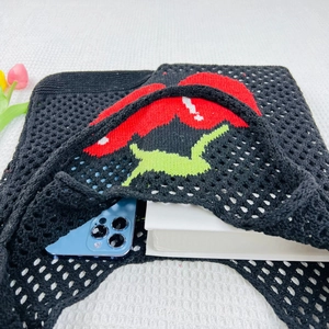 Detailed close-up of a black knit tote bag showing spacious storage for a phone and book