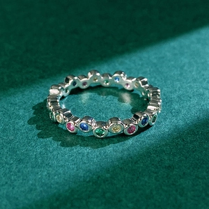 Macro shot of colorful zircon stones in a silver setting over a green textured background