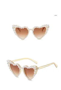Detailed views of champagne heart-shaped sunglasses with faux pearl edges and glitter arms