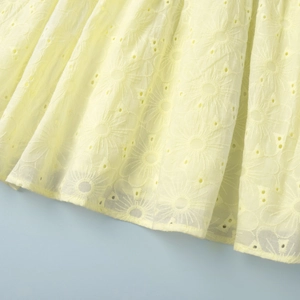 Close-up of yellow cotton summer dress featuring intricate floral eyelet embroidery detail