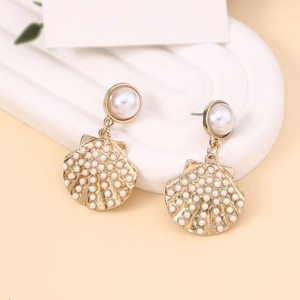 Detail of elegant gold shell drop earrings with white pearls on a minimalist background