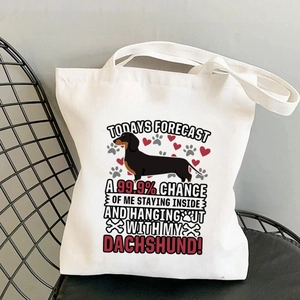 Detailed view of white canvas tote bag with funny Dachshund print on a black wire chair