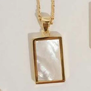 Macro shot of rectangular gold-plated shell pendant and fine chain texture detail