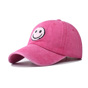 Detail view of pink washed cotton baseball cap with embroidered smiley face patch