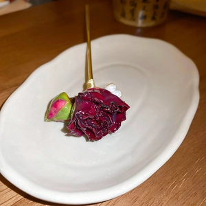 Dettaglio forcina per capelli con rosa rossa vintage e perle su piatto in ceramica