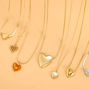 Polished gold and silver heart pendant necklaces in various chain styles on an orange background