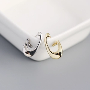Close-up of minimalist U-shaped s925 silver earrings in gold and silver finish