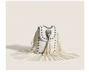 Detail of white leather crossbody bag with silver skull buckle and long fringe tassels