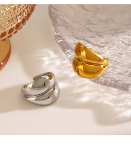 Detail of polished chunky teardrop rings in gold and silver finish with wavy texture