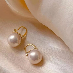 Macro detail of elegant gold-plated pearl earrings on soft silk background texture