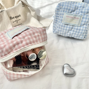 Macro detail of quilted berry plaid cosmetic bag showing large opening and soft texture