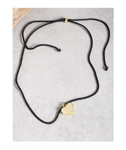 Detail of a gold heart pendant on a black adjustable cord necklace over a grey background
