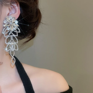Gros plan d'un mannequin portant des boucles d'oreilles fleurs argentées avec pompons strass