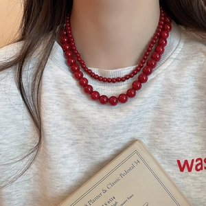 Detail of layered red glass bead necklace showing the contrast of large and small beads
