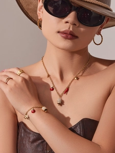 Vue détaillée d'une parure de bijoux dorés avec breloques coccinelle et piment sur mannequin