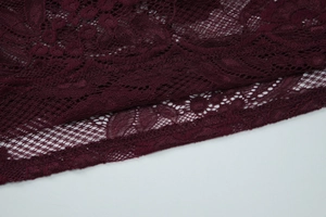 Macro shot of dark red lace fabric with intricate floral patterns and hollow-out detailing