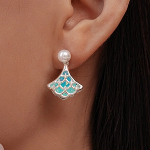 Detailed view of luxury ginkgo leaf earring featuring a white pearl and blue opal inlay