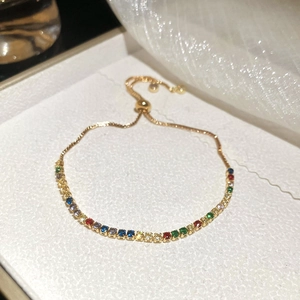 Macro view of adjustable gold tennis bracelet with multi-color zircon stones in a box