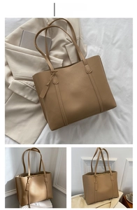 Detail shot of khaki leather tote bag with long handles and matching charm tag