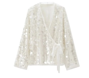 Detail view of white sequin patchwork design on long sleeve wrap style blouse
